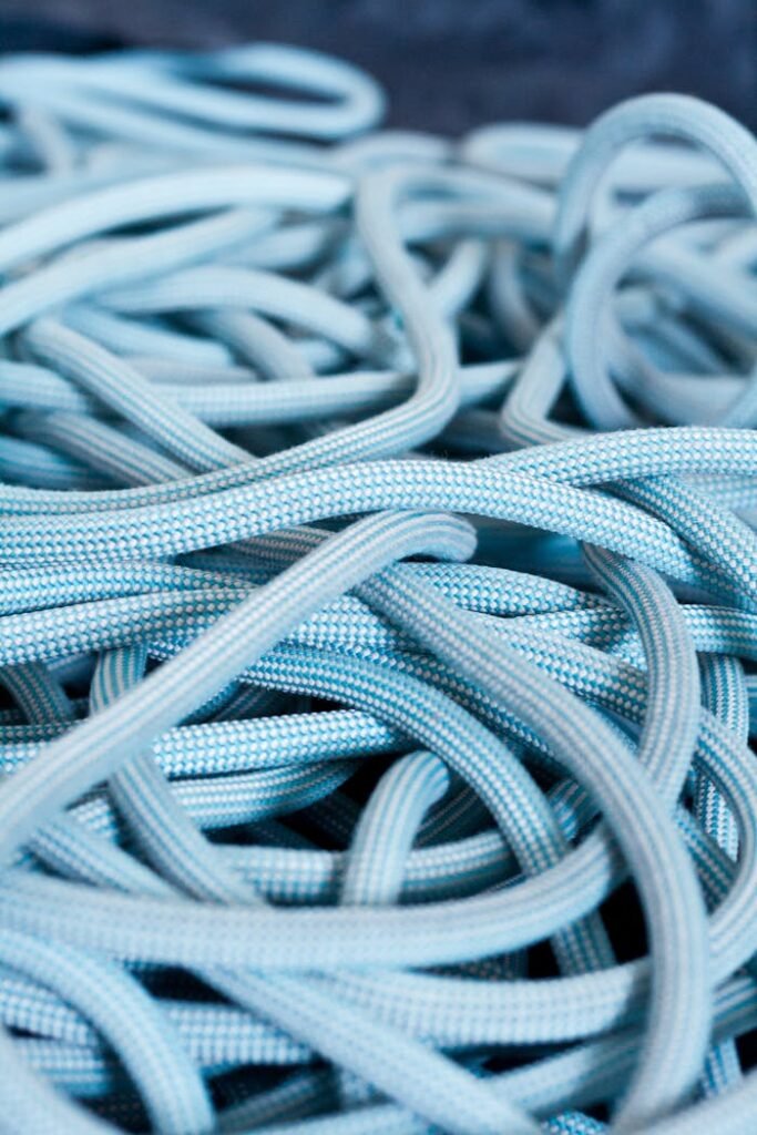 Detailed view of blue climbing rope tangled on a surface, showcasing texture and patterns.